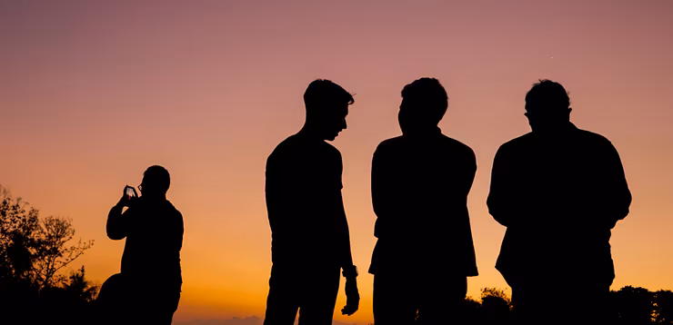 Silhouette of men in front of a sunset
