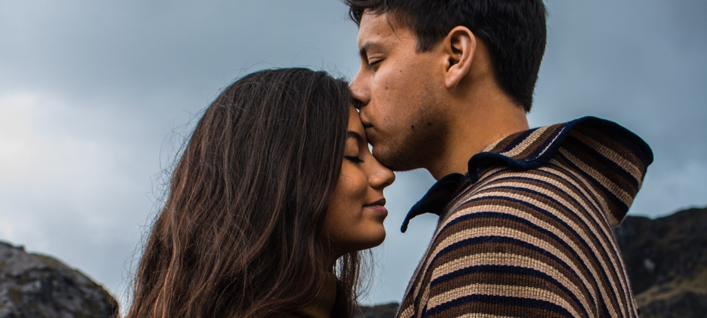 Man kisses woman's forehead