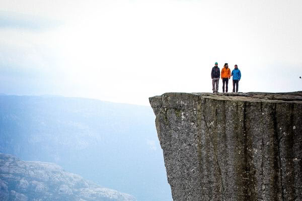 Three people standing at the top of a cliff