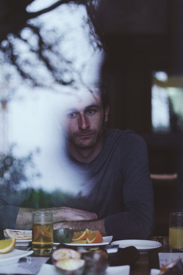 Man gazing out a window, looking forlorn