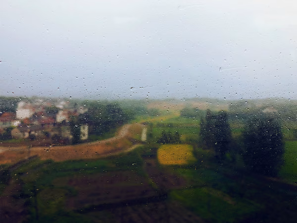 A rural countryside viewed through a window in the rain